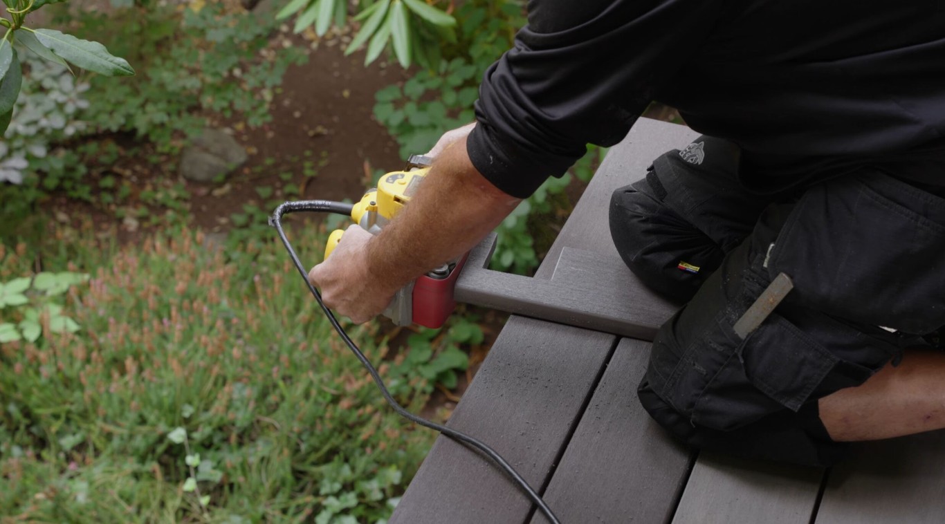 Professional installing composite deck boards with power tools